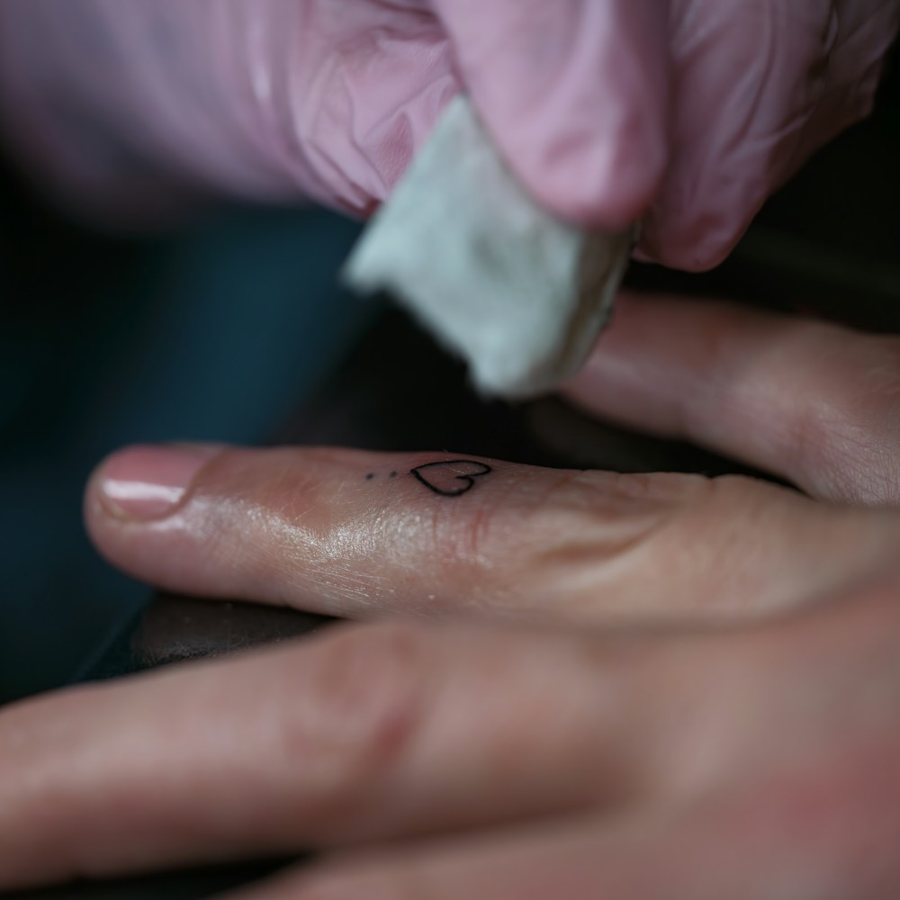 Referência fotográfica de uma pequena tatuagem de coração no dedo
